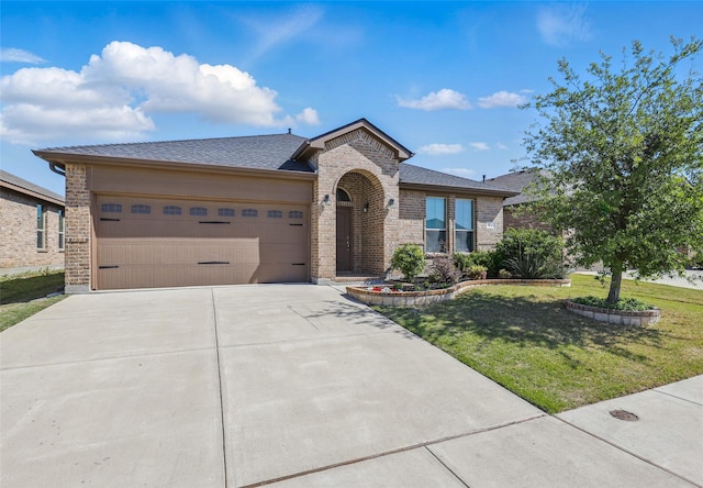 view of front facade featuring an attached garage, driveway, a front lawn, and brick siding