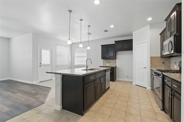 kitchen featuring tasteful backsplash, light tile patterned floors, a sink, appliances with stainless steel finishes, and light stone counters