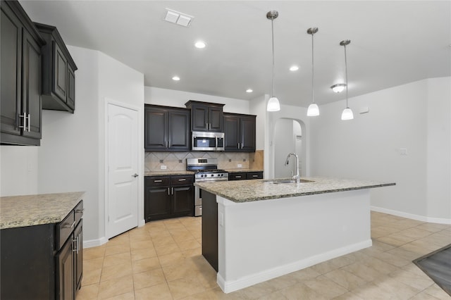 kitchen featuring light tile patterned flooring, decorative backsplash, a sink, and appliances with stainless steel finishes