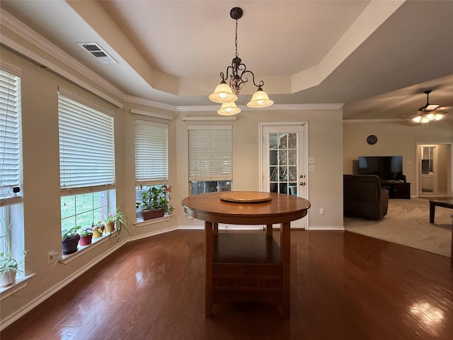 dining space featuring a raised ceiling, baseboards, wood finished floors, visible vents, and ornamental molding