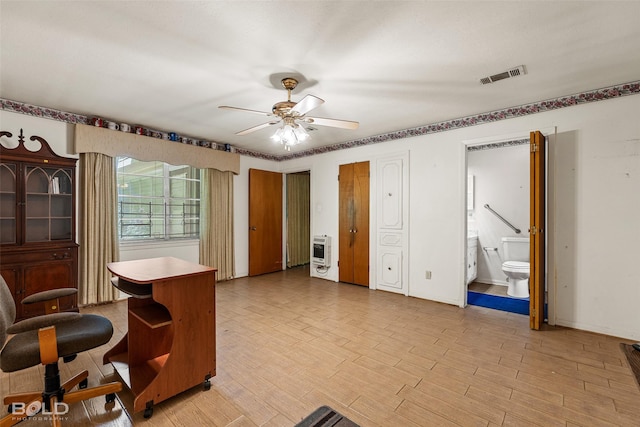 interior space featuring light wood-type flooring, a ceiling fan, visible vents, and heating unit