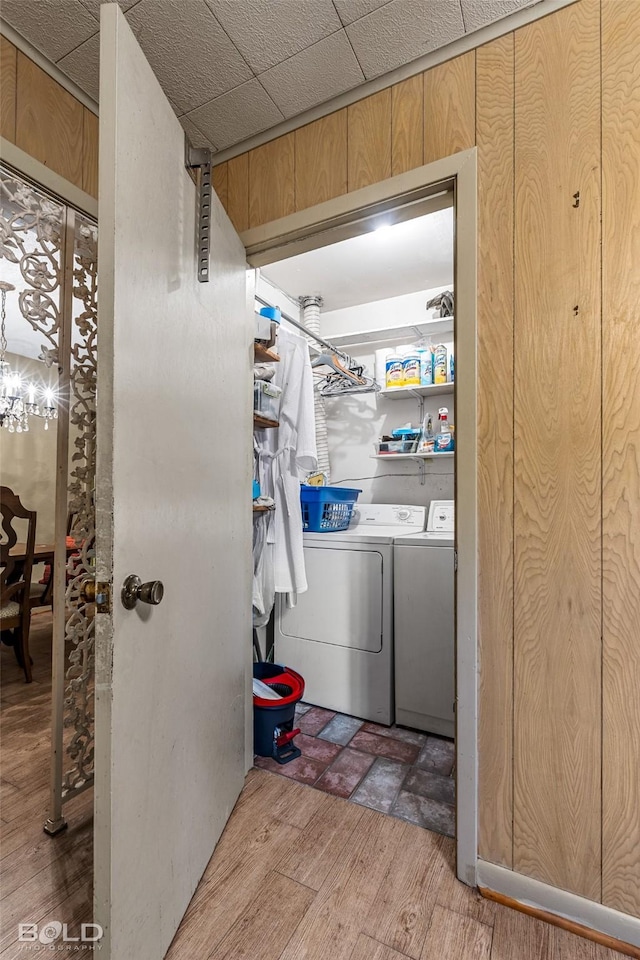 laundry area with washing machine and clothes dryer, an inviting chandelier, laundry area, and wood finished floors