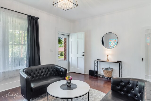 living area with ornamental molding, baseboards, an inviting chandelier, and wood finished floors