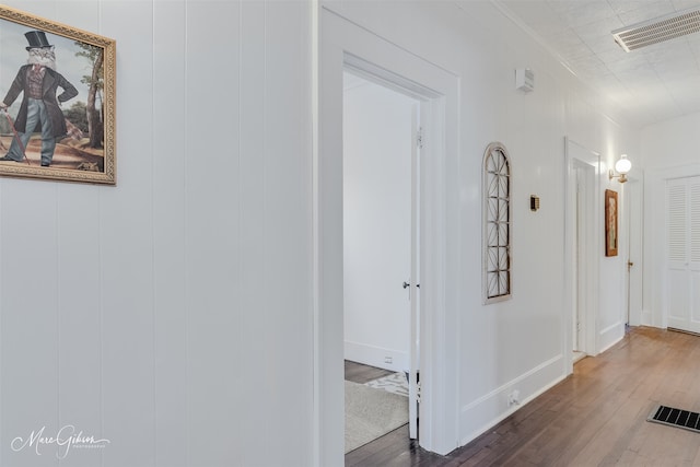 corridor with wood finished floors, visible vents, and ornamental molding