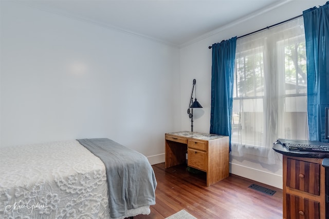 bedroom featuring crown molding, visible vents, baseboards, and wood finished floors