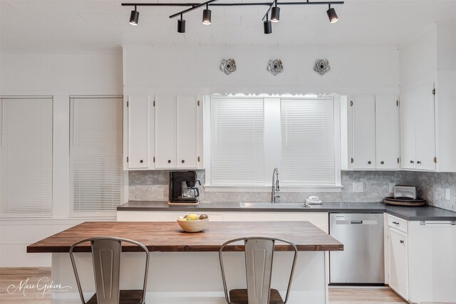 kitchen with a center island, a sink, backsplash, white cabinetry, and dishwasher