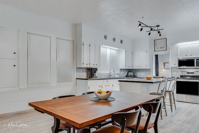 kitchen featuring dark countertops, light wood-type flooring, appliances with stainless steel finishes, and white cabinetry