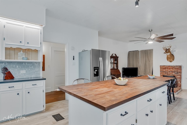 kitchen with light wood-style flooring, stainless steel refrigerator with ice dispenser, and butcher block counters
