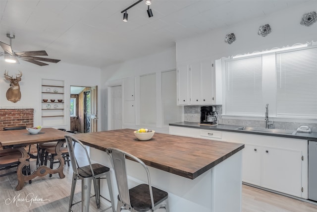 kitchen featuring a sink, white cabinets, light wood-style floors, and butcher block counters