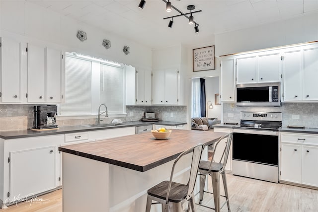 kitchen featuring a sink, decorative backsplash, white cabinets, and stainless steel appliances