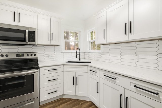 1507 Newport Ave, Dallas, TX 75224 - kitchen with light stone counters, a sink, stainless steel appliances, white cabinets, and dark wood-style flooring