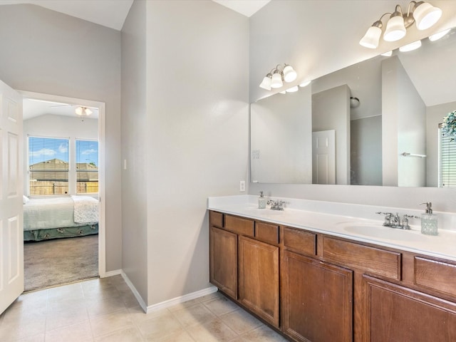 ensuite bathroom with a sink, double vanity, vaulted ceiling, baseboards, and ensuite bathroom