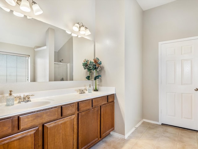 full bath with baseboards, a sink, a shower stall, and double vanity