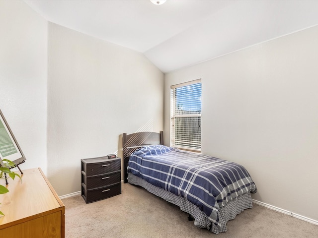 bedroom with baseboards, vaulted ceiling, and light colored carpet