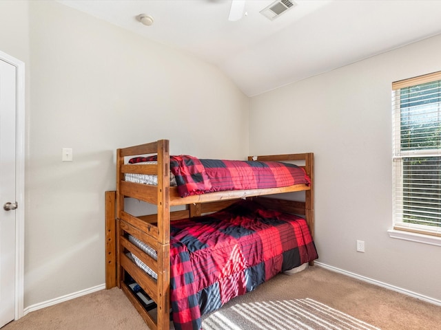 carpeted bedroom featuring baseboards, vaulted ceiling, visible vents, and a ceiling fan