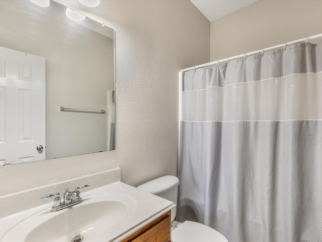 bathroom with a textured wall, vanity, and toilet