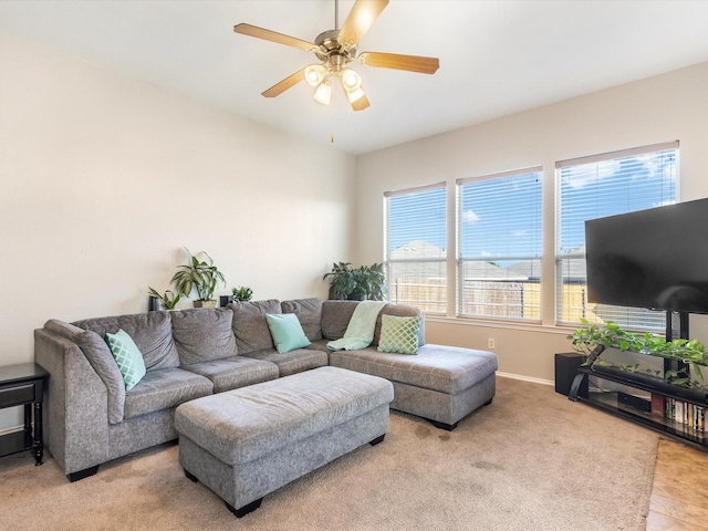 living area featuring a ceiling fan, baseboards, and light carpet