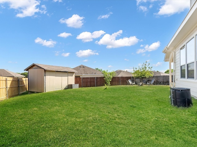 view of yard featuring a storage shed, an outbuilding, and a fenced backyard