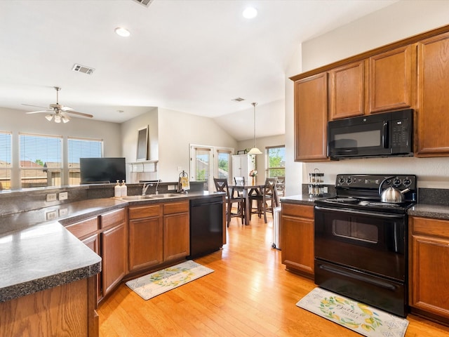 kitchen with a sink, dark countertops, visible vents, brown cabinets, and black appliances