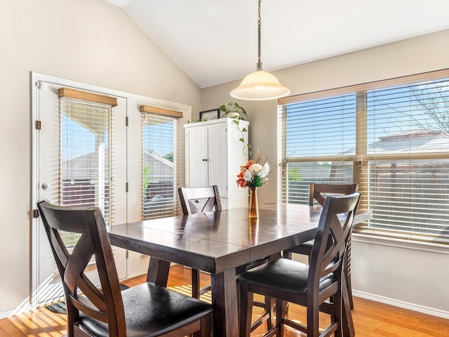 dining room with vaulted ceiling, light wood-type flooring, and baseboards