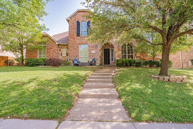 traditional-style home with a shingled roof, brick siding, and a front yard