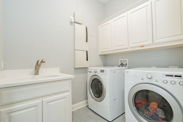 laundry room featuring baseboards, a sink, independent washer and dryer, and cabinet space