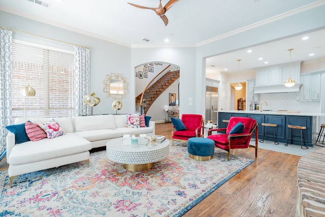 living area with light wood finished floors, recessed lighting, stairway, ceiling fan, and ornamental molding