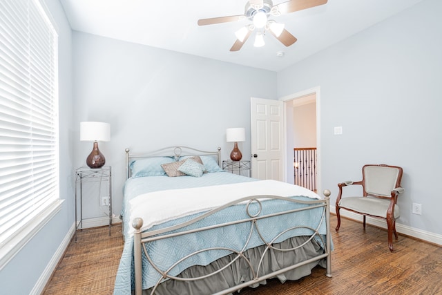 bedroom featuring wood finished floors, a ceiling fan, baseboards, and multiple windows