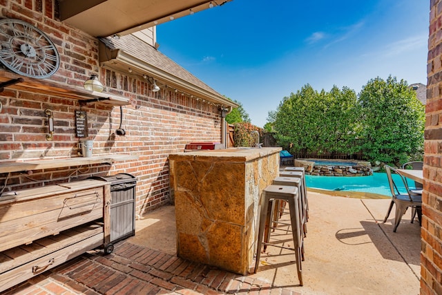 view of patio / terrace with exterior bar, a hot tub, a swimming pool, and fence
