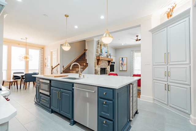 kitchen with light countertops, blue cabinets, a sink, crown molding, and appliances with stainless steel finishes