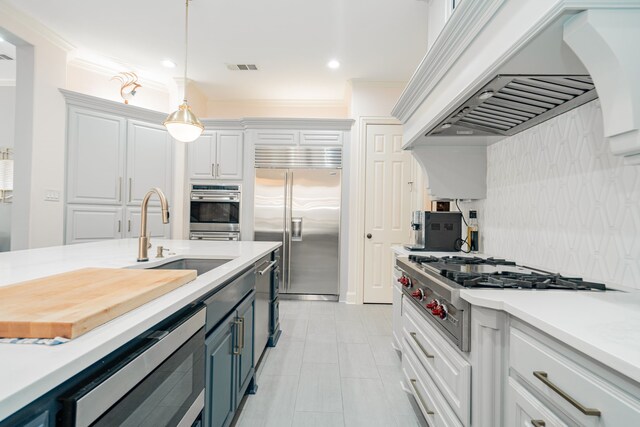 kitchen featuring light countertops, appliances with stainless steel finishes, a sink, and custom range hood