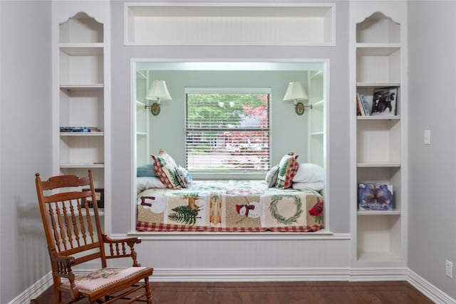 sitting room with built in shelves and wood finished floors