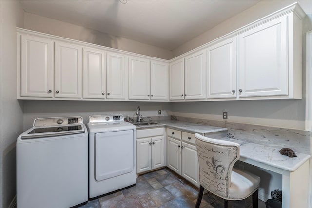 washroom featuring cabinet space, washing machine and dryer, stone finish flooring, and a sink