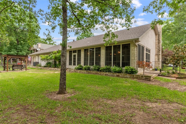 rear view of house with a lawn, a gazebo, fence, and stone siding