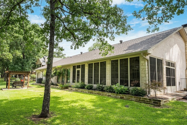 rear view of house featuring a gazebo, central AC, stone siding, a shingled roof, and a yard