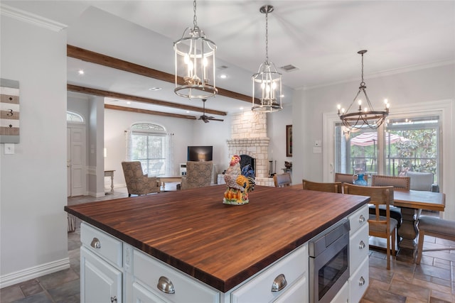 125 Bay Tree Trl, Mabank, TX 75156 - kitchen with wood counters, stainless steel microwave, a chandelier, a stone fireplace, and open floor plan
