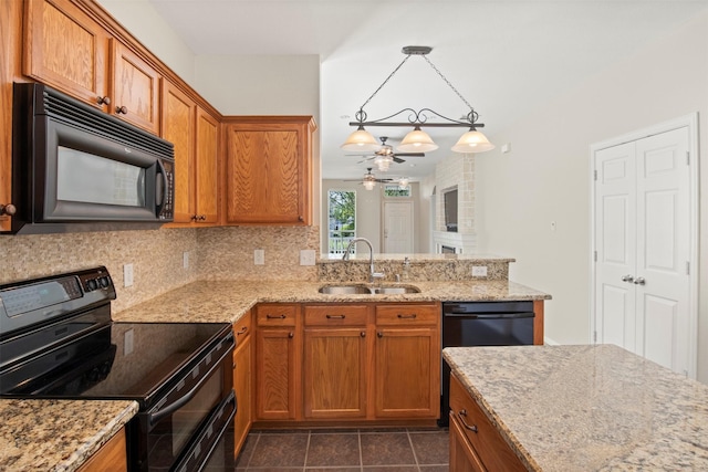 kitchen with a sink, decorative backsplash, light stone countertops, brown cabinetry, and black appliances