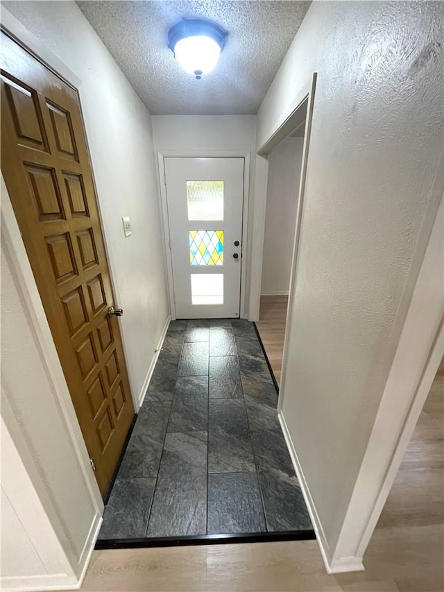 doorway featuring stone finish flooring, baseboards, and a textured ceiling