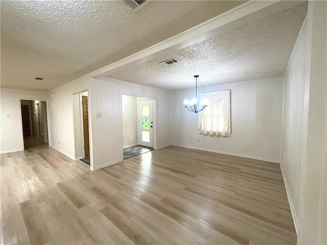 empty room featuring wood finished floors, a textured ceiling, and an inviting chandelier