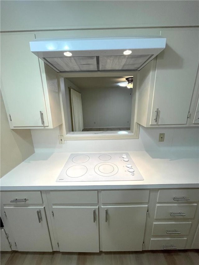 room details featuring white cabinetry, range hood, light countertops, and white electric stovetop