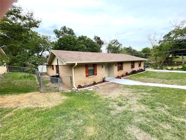 view of front of house featuring roof with shingles, a front lawn, a gate, fence, and brick siding