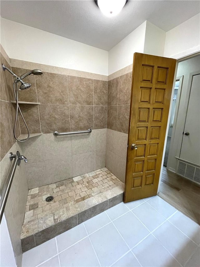 full bath featuring tile patterned floors, visible vents, and tiled shower