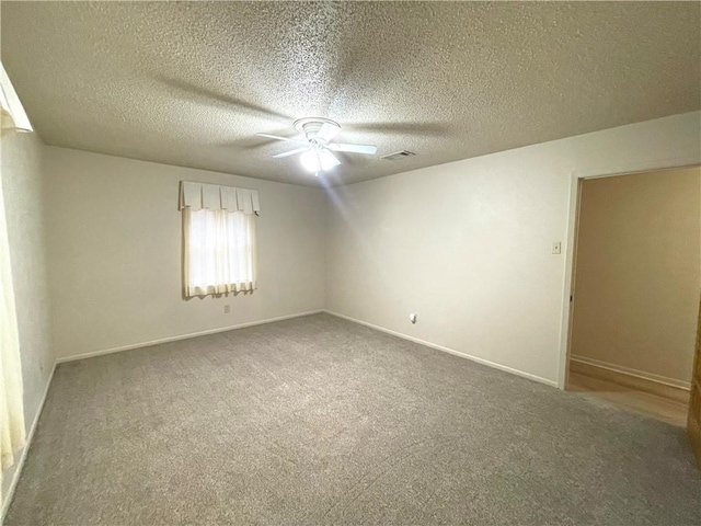 spare room featuring a ceiling fan, visible vents, carpet floors, and a textured ceiling
