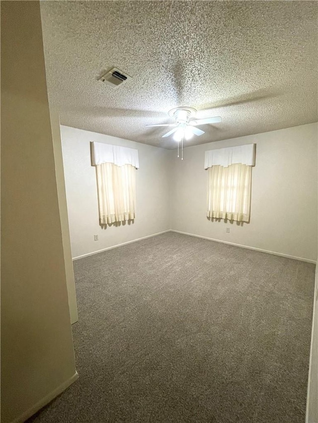 carpeted empty room featuring ceiling fan, baseboards, a textured ceiling, and visible vents