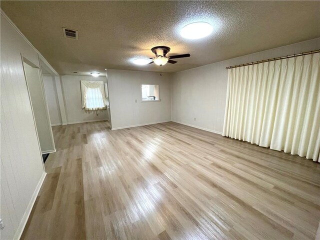 unfurnished room featuring wood finished floors, visible vents, a ceiling fan, baseboards, and a textured ceiling