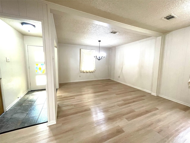 unfurnished dining area with an inviting chandelier, wood finished floors, visible vents, and a textured ceiling