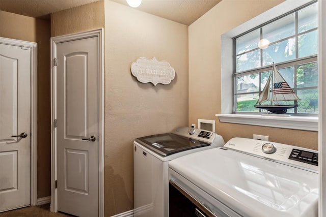 clothes washing area featuring a textured wall, washer and dryer, and laundry area