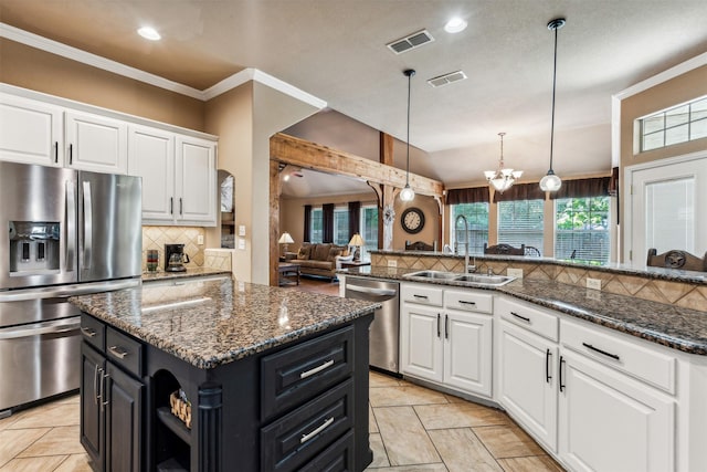 kitchen with stainless steel appliances, backsplash, a sink, a kitchen island, and white cabinetry