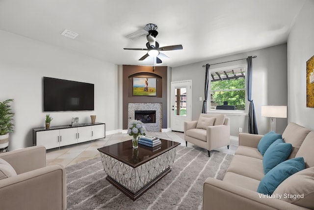 tiled living room featuring baseboards, a ceiling fan, visible vents, and a tile fireplace