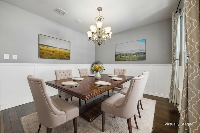 dining space featuring wainscoting, wood finished floors, visible vents, and a notable chandelier